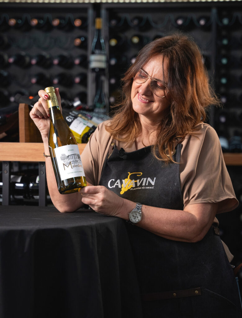 Caviste CAVAVIN présentant une bouteille de vin en magasin